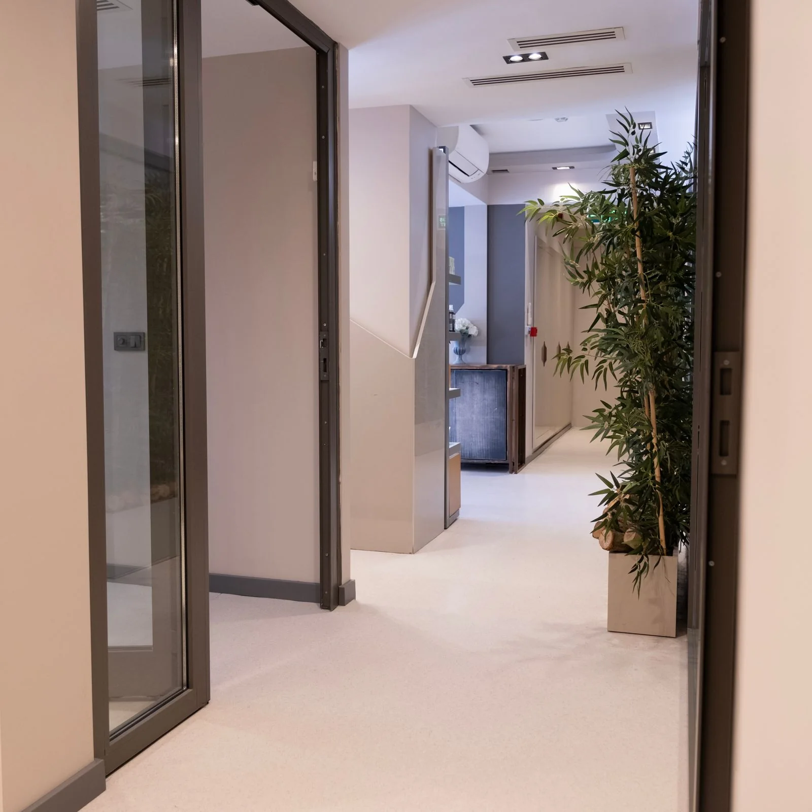 A bright, empty clinic corridor with glass doors.
