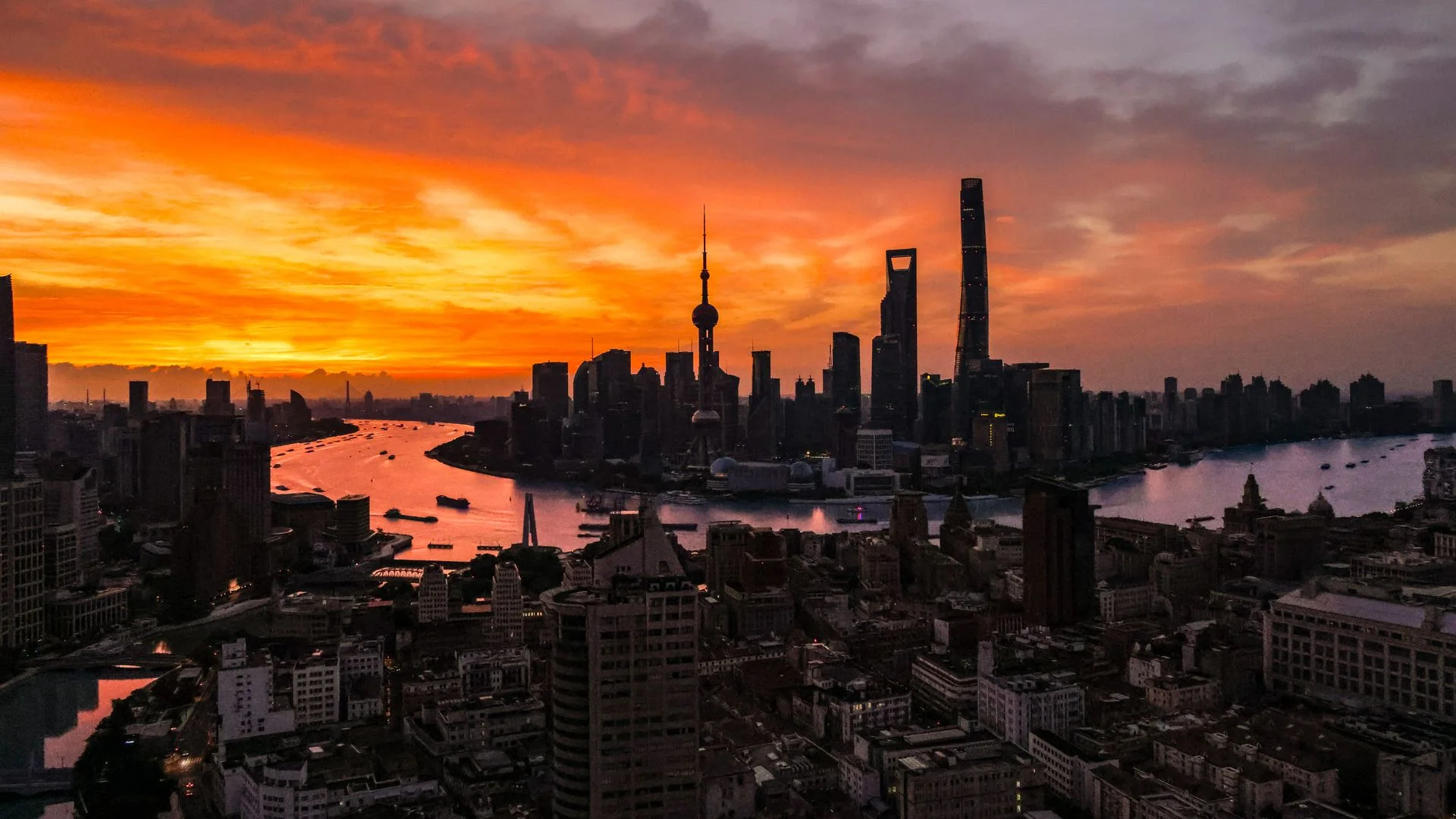 The Shanghai skyline at sunset over the Huangpu River.